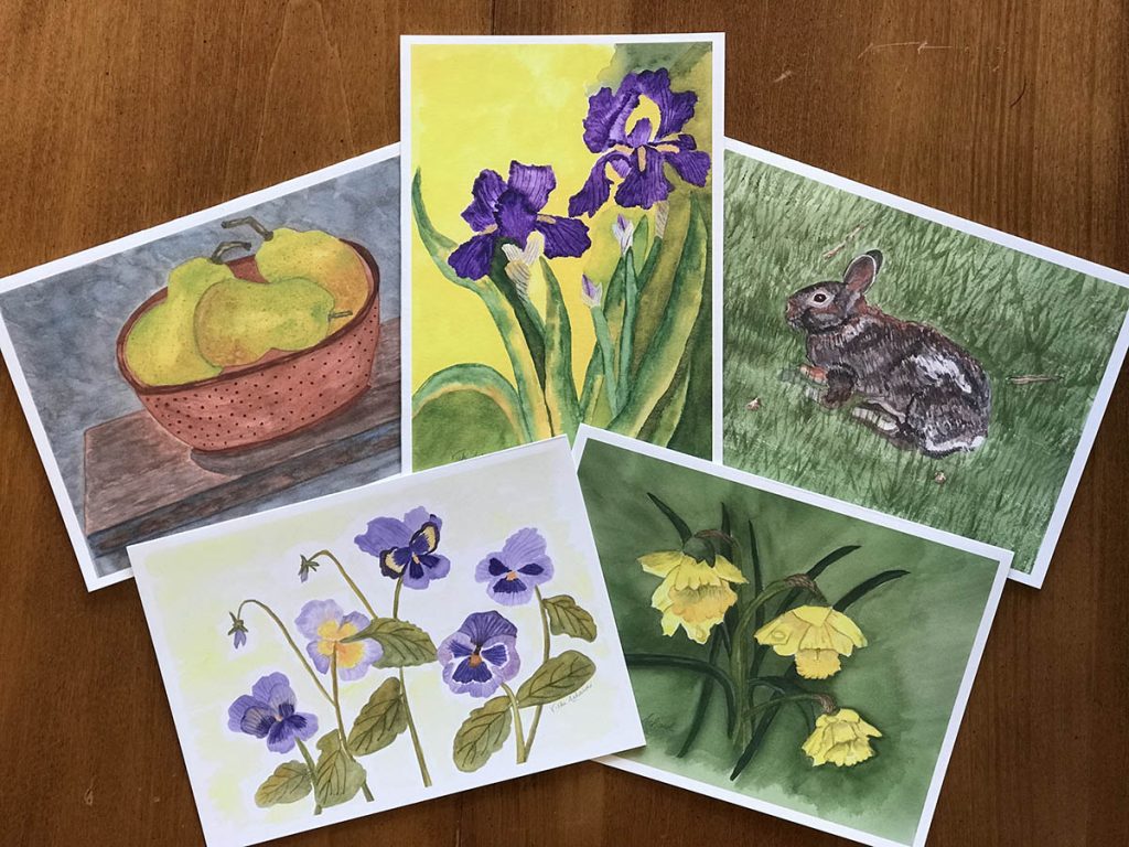 Five watercolor cards of flowers, bunny, and bowl of pears on dark board